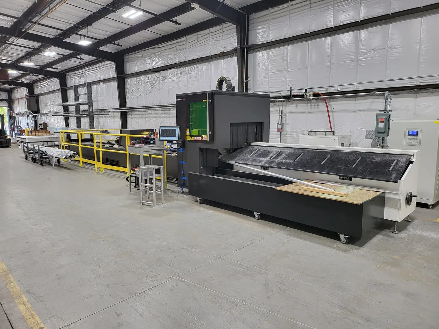 Fiber laser cutting machine with a tube-feed conveyor on the shop floor.